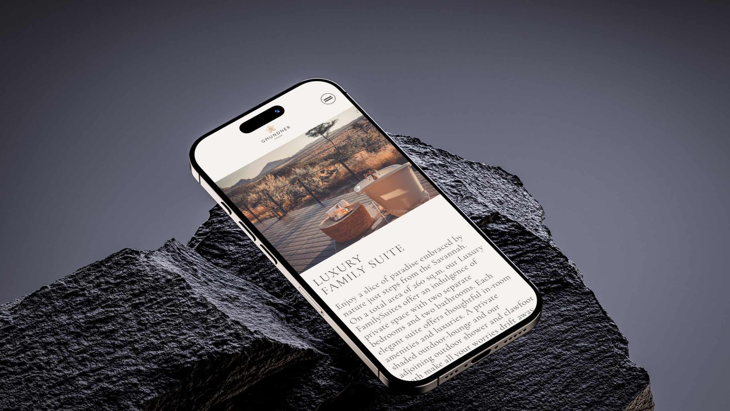 Smartphone zeigt Website der Gmundner Lodge Namibia mit Luxus-Familien-Suite.