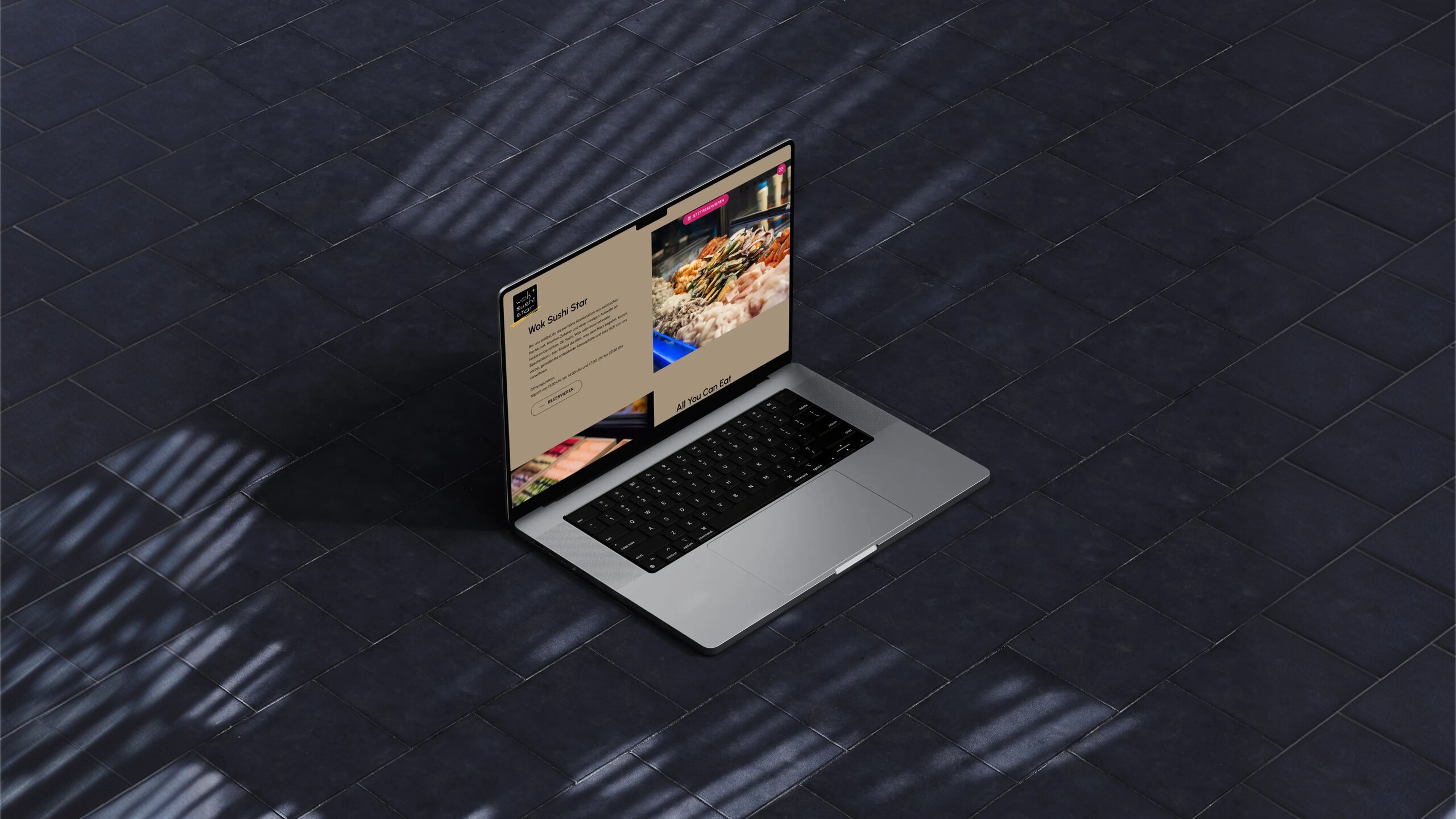 Laptop mit Website-Design auf dunklem Boden, digitaler Arbeitsplatz.